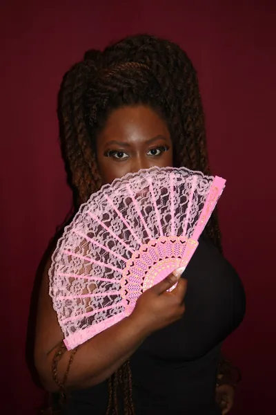 Portrait studio d'une membre de MTL Students tenant un éventail rose.